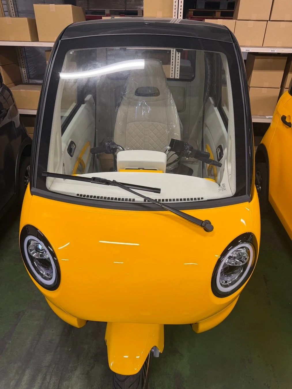 倉庫に駐車された黄色の三輪小型モビリティ