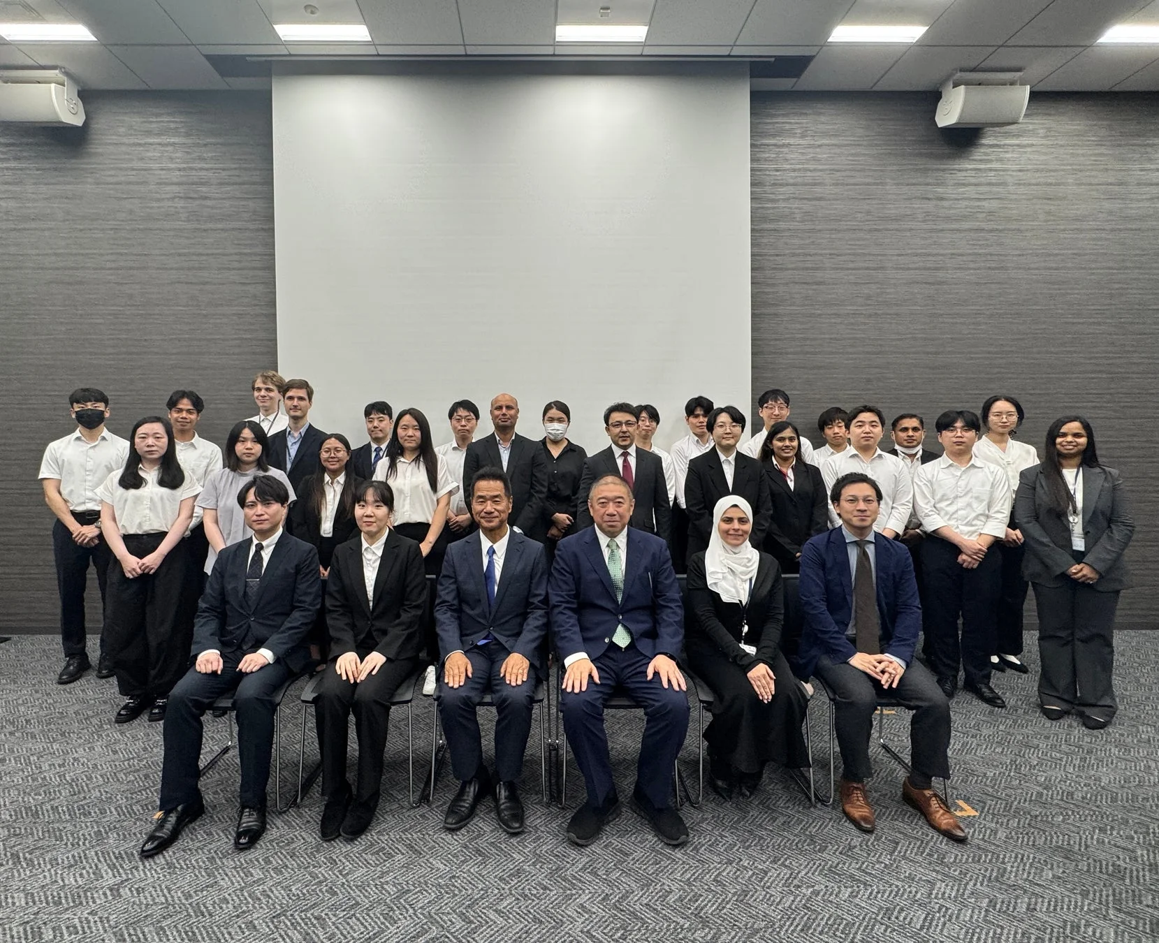 多様な人々が写る会議室での集合写真