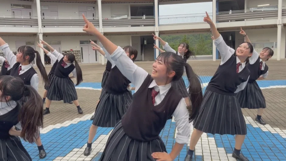 女子高生が制服姿で楽しそうにダンスのようなポーズをとっています