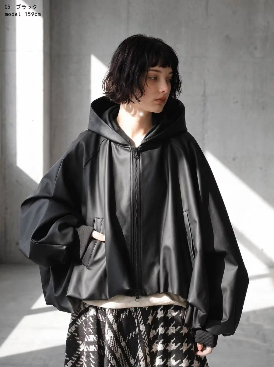 黒いフェイクレザー風フードジャケットと千鳥格子のスカートを着用した女性のファッションスナップ