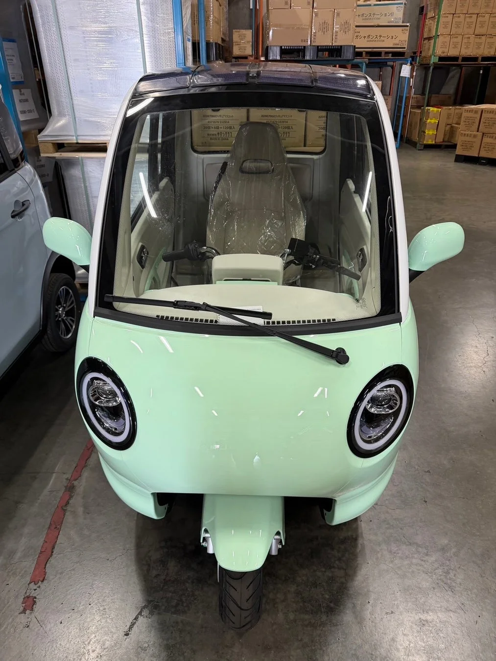 倉庫に停められたミントグリーンの三輪電動自動車