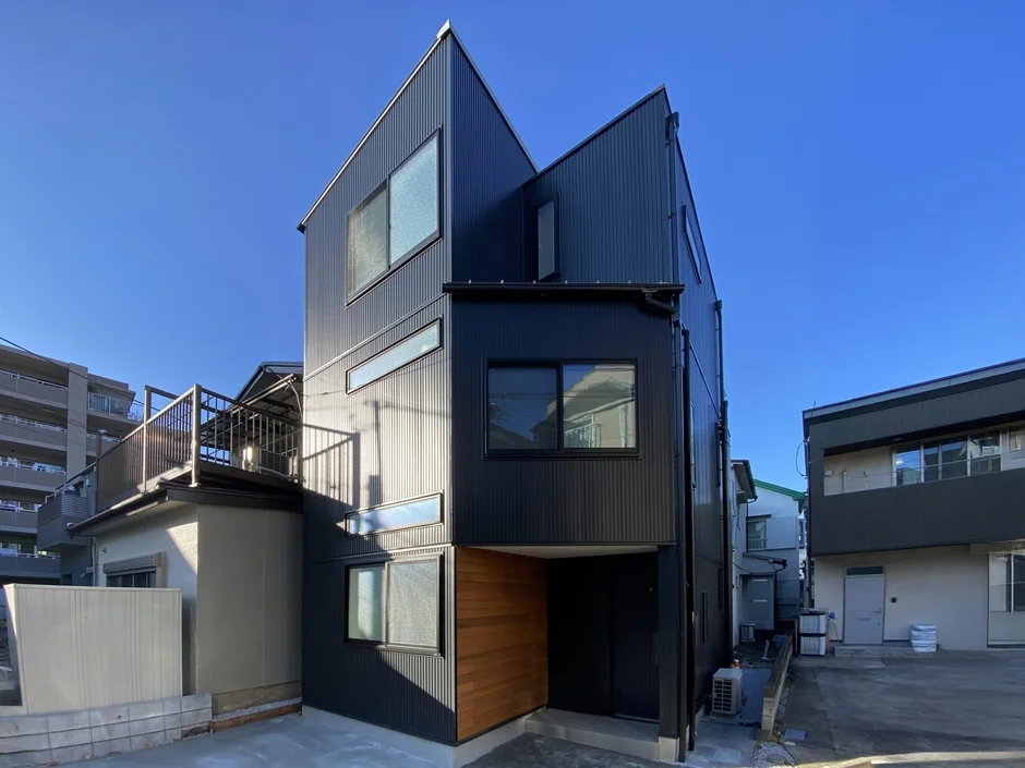 黒い外壁と特徴的な多角形の屋根を持つモダンな住宅