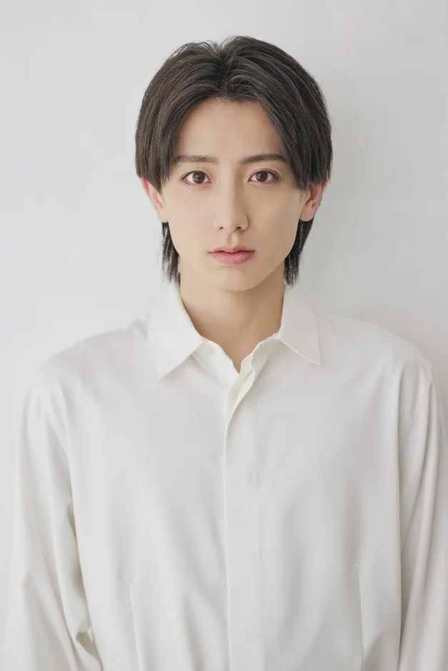 白いシャツを着た若い男性がカメラをまっすぐ見つめているポートレート写真です。