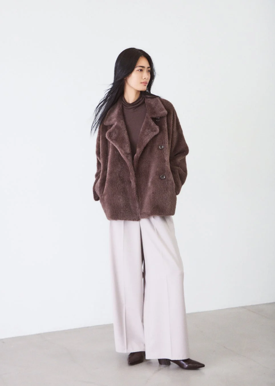 ファーコートとベージュのワイドパンツの女性