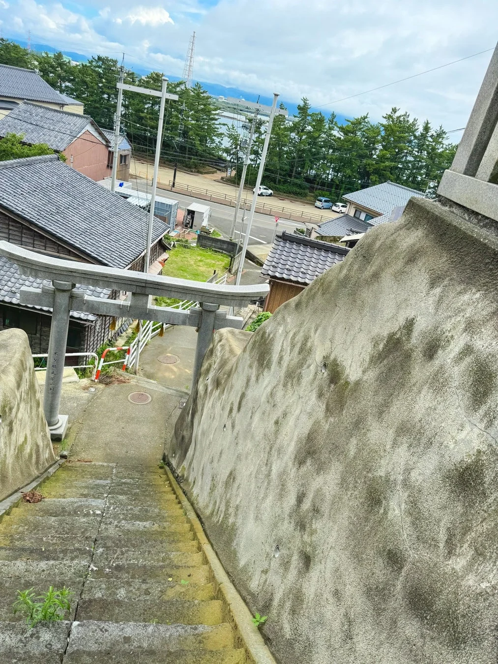 石段と鳥居の向こうに町並みと海が見える風景