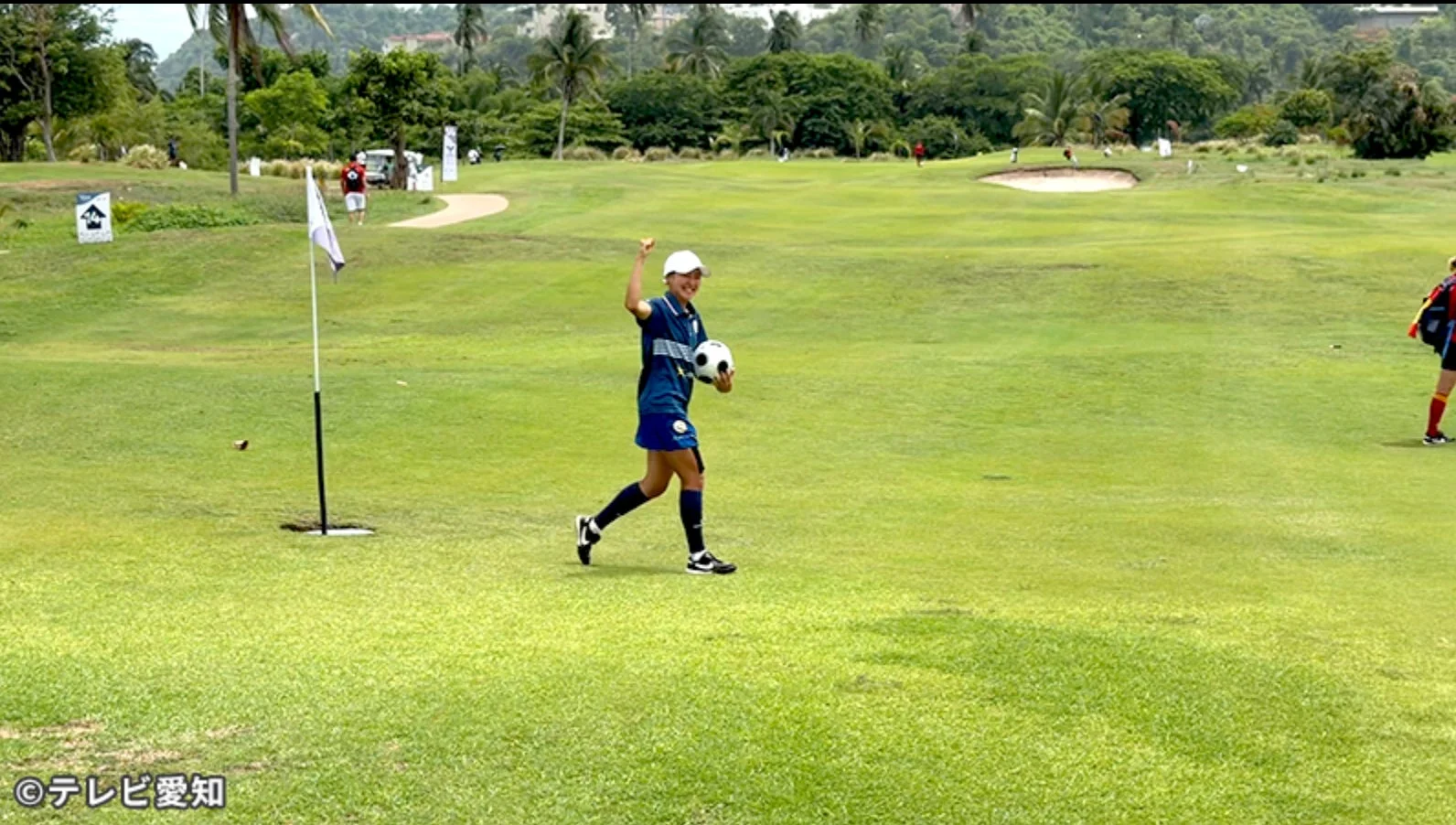 ゴルフコースでサッカーボールを持つ女性選手