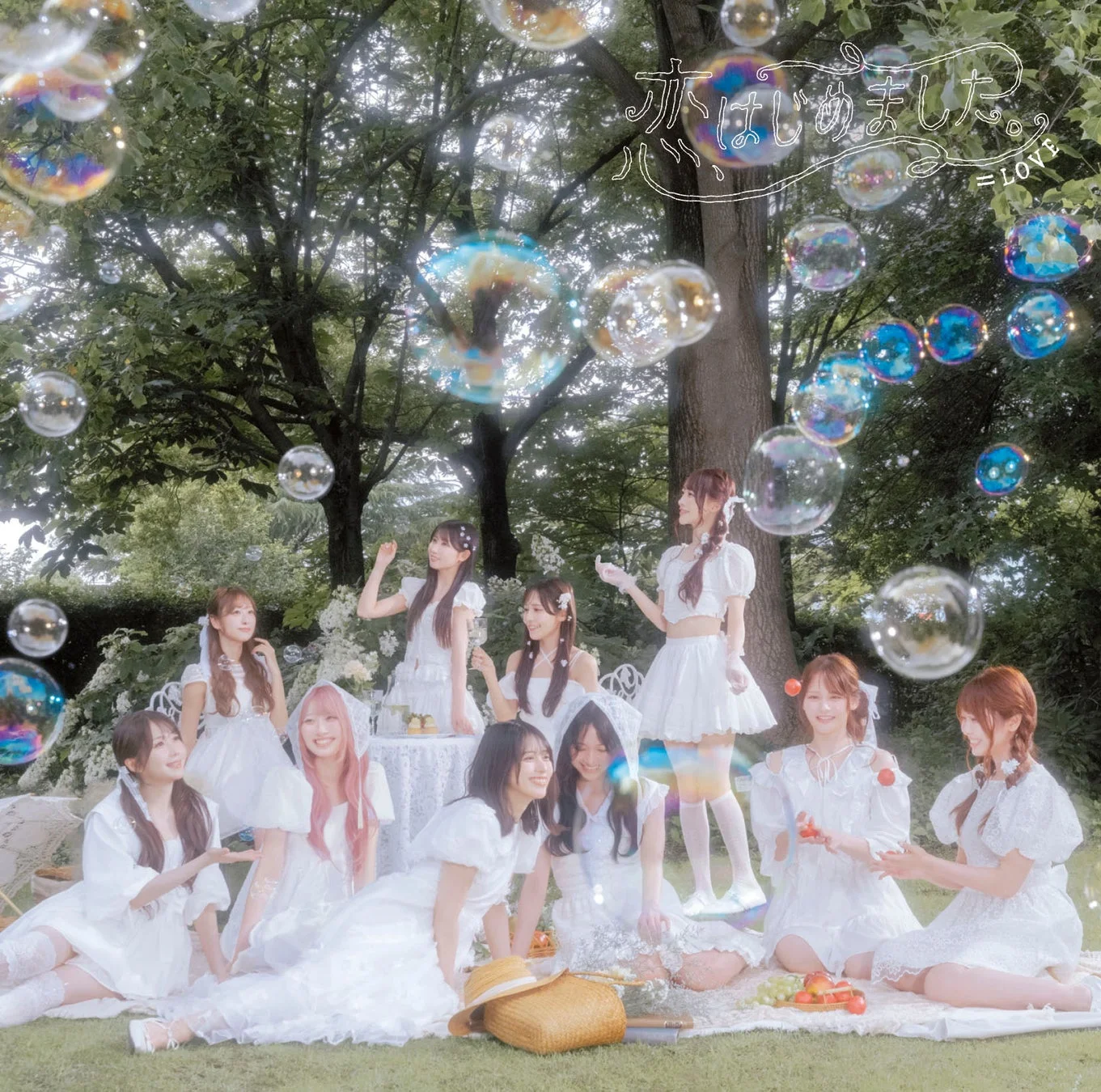 白いドレスを着た女性アイドルグループが屋外でシャボン玉が舞う中でピクニックをしている写真