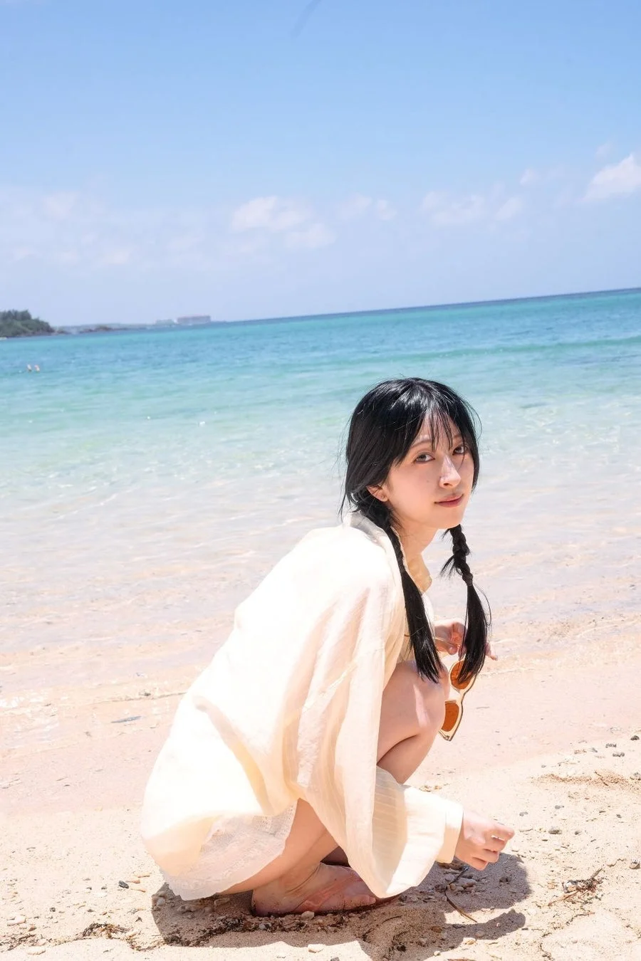 ビーチでツインテールの月音こなさんが笑顔を見せています