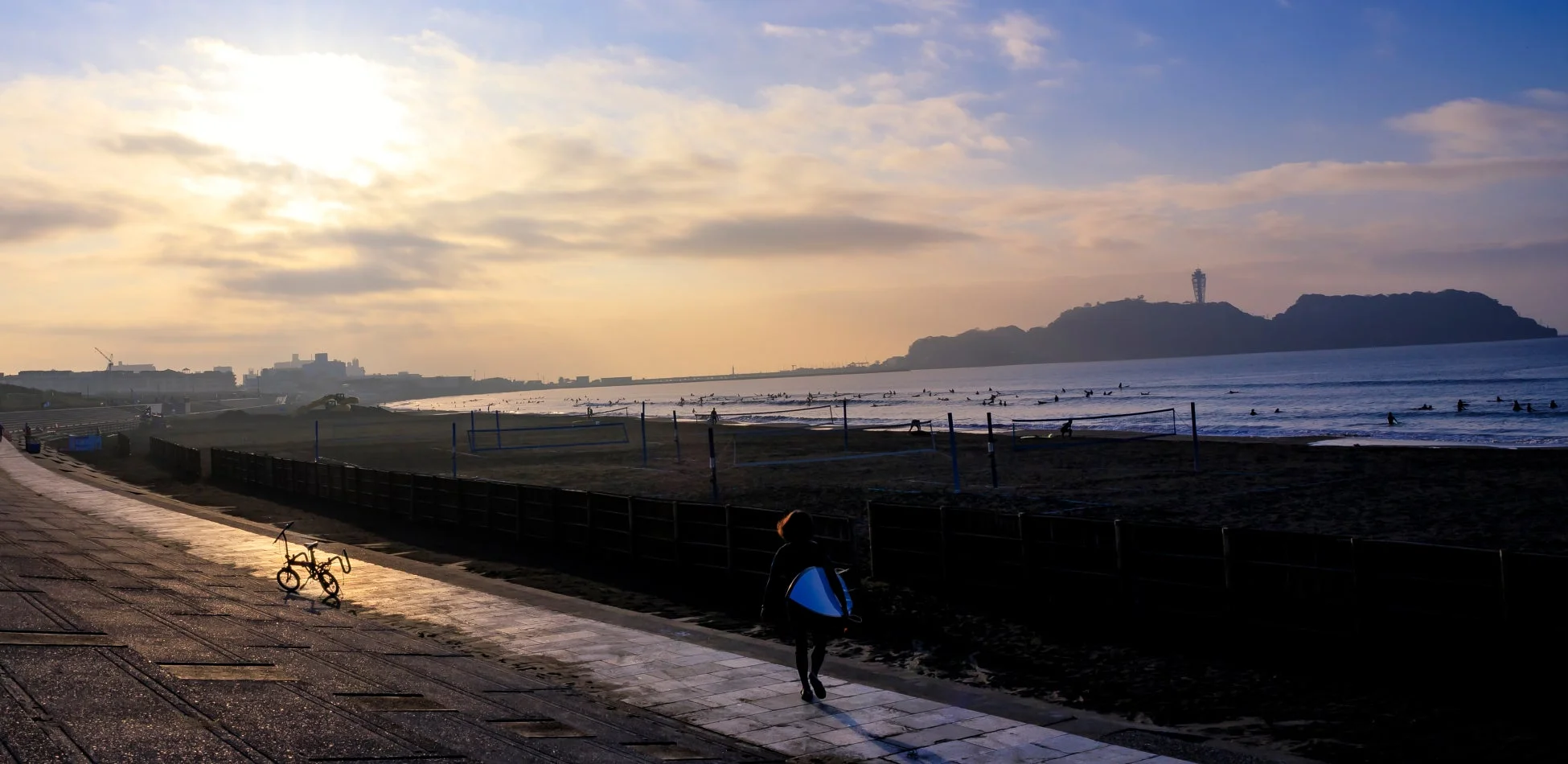 夕焼けの海でサーフィンを楽しむ人々