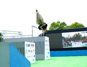 屋外のイベント会場で、男性が鉄棒の上でアクロバティックなバックフリップを披露している様子。