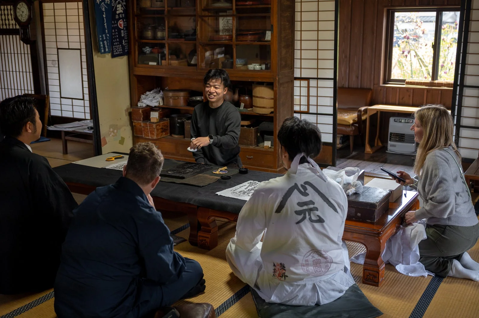 日本の文化、伝統家屋、書道、ワークショップ、人々、畳、障子、日本、文化体験、アジア、室内、グループ、交流、芸術、工芸、和装、笑顔、学び、旅行、歴史