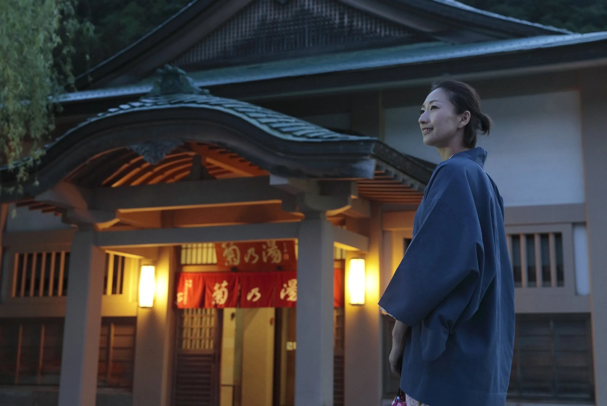 夕暮れ時、日本の伝統的な建物の前で浴衣を着た女性