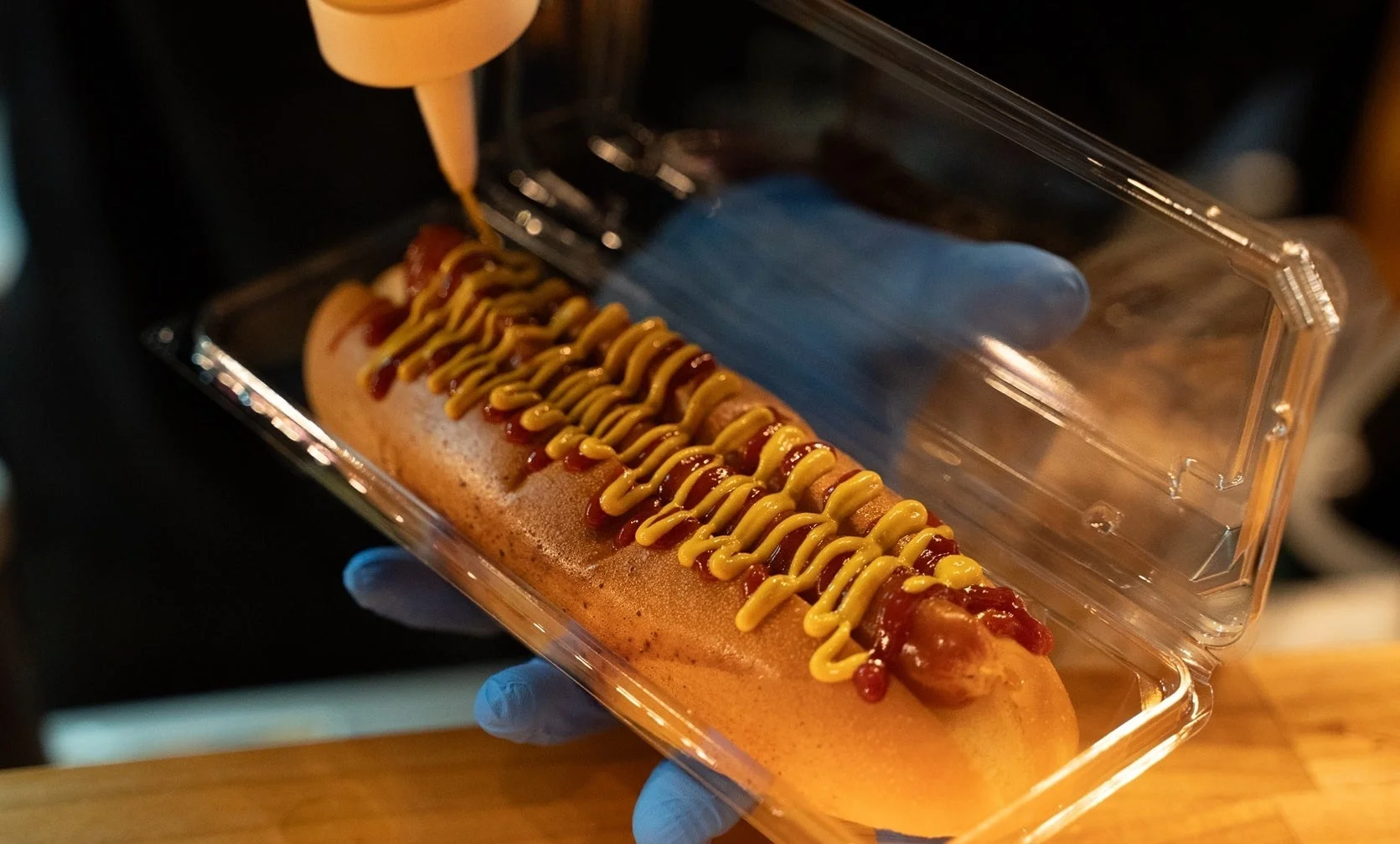ホットドッグにケチャップとマスタードをかける様子