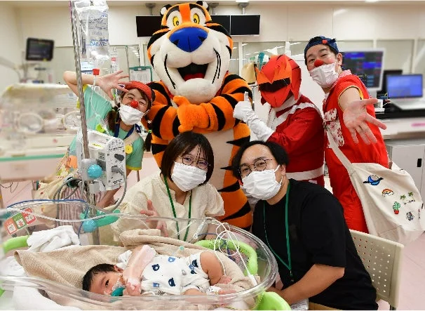 NICUで赤ちゃんを囲むトニー・ザ・タイガーとクリニクラウン