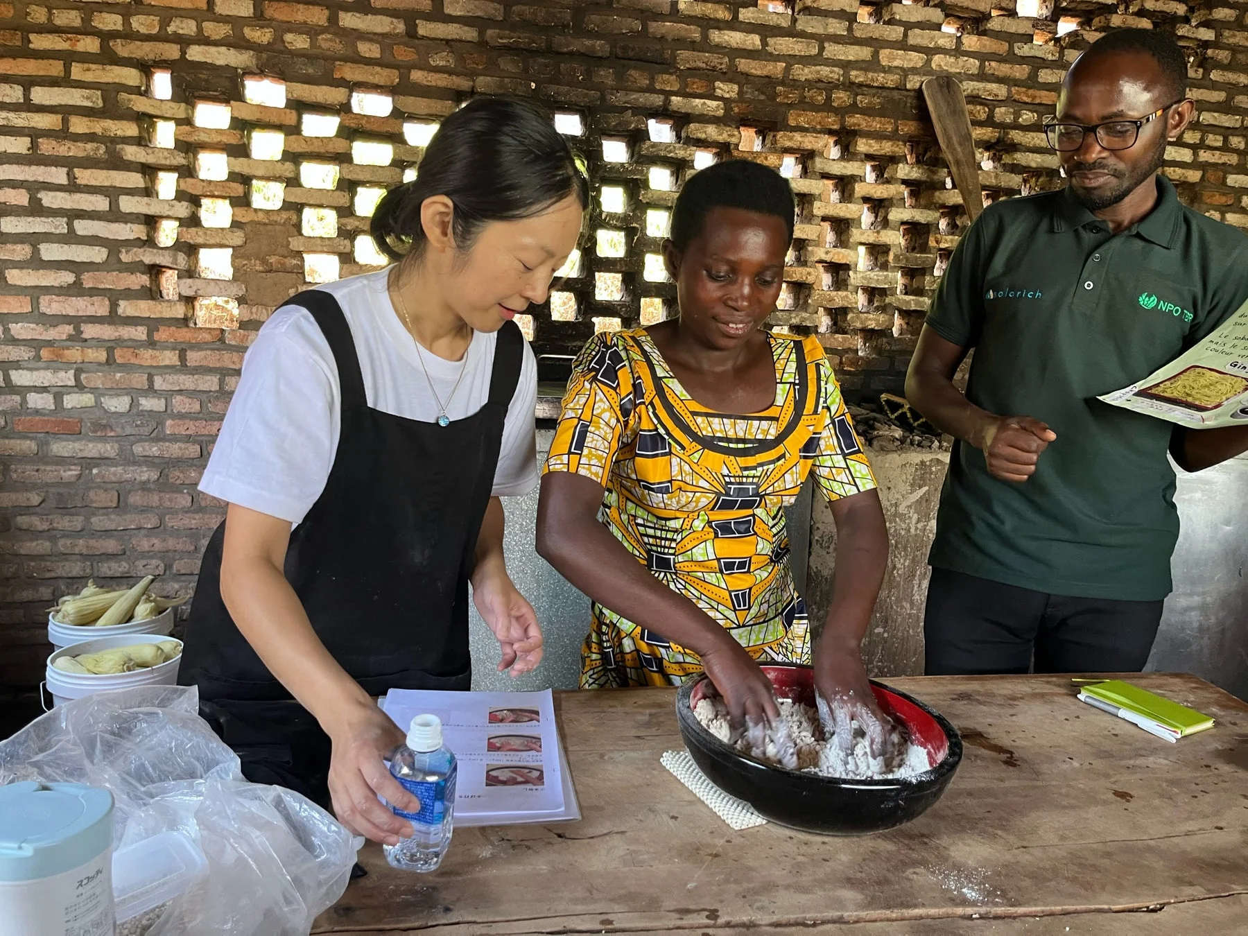 3人の人々が協力して料理をし、女性が生地をこねている様子
