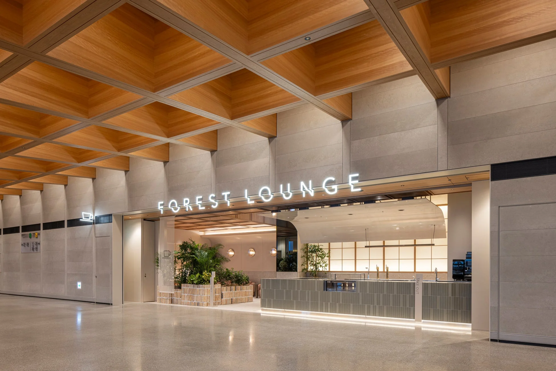 木製の格子天井が特徴的な、モダンで広々としたラウンジの入り口。ネオンサインで「FOREST LOUNGE」と表示され、バーカウンターや緑豊かな植物が配された、落ち着いた雰囲気の空間が広がっています。