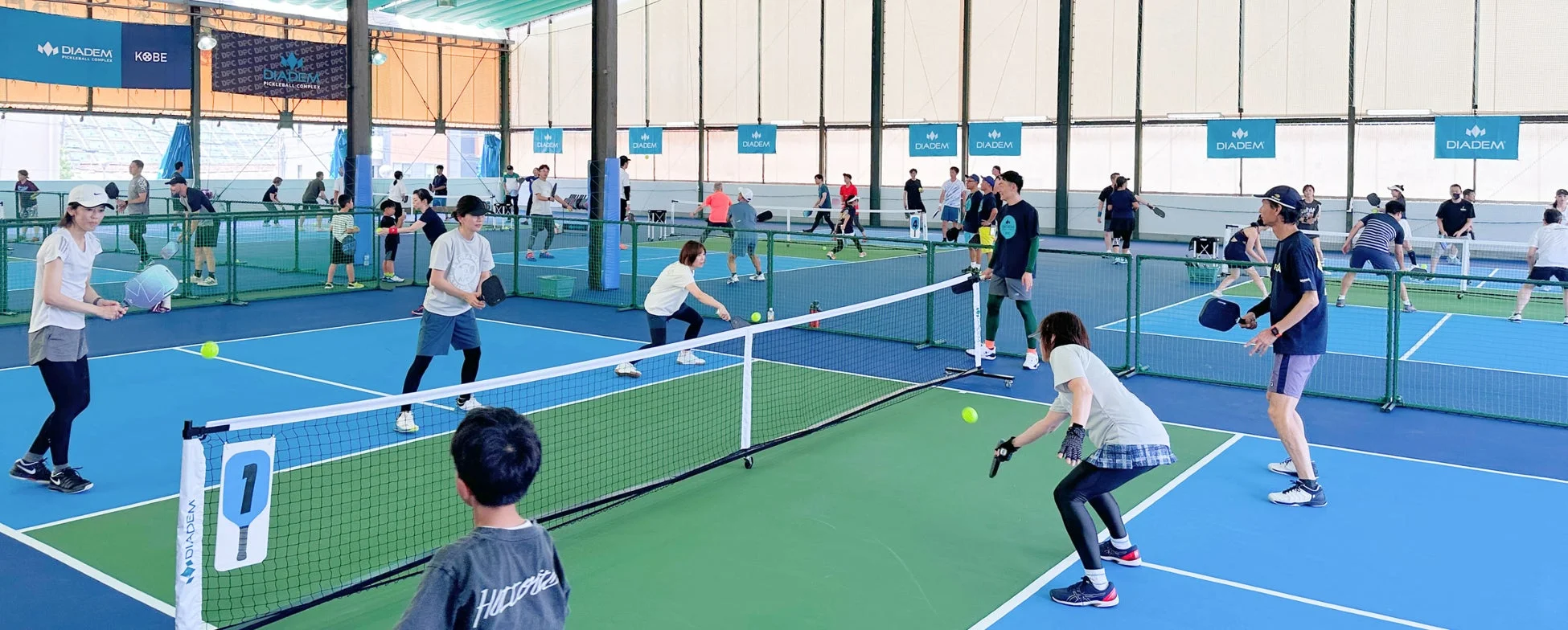 大人から子供まで多くの人々がピックルボールを楽しんでいる様子