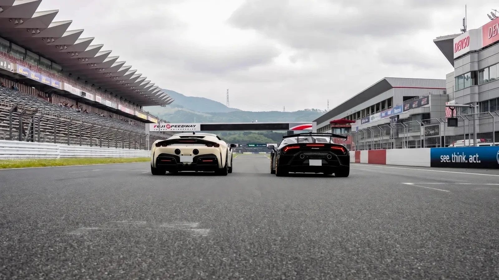 富士スピードウェイのサーキットで並んで走行する高級スポーツカー