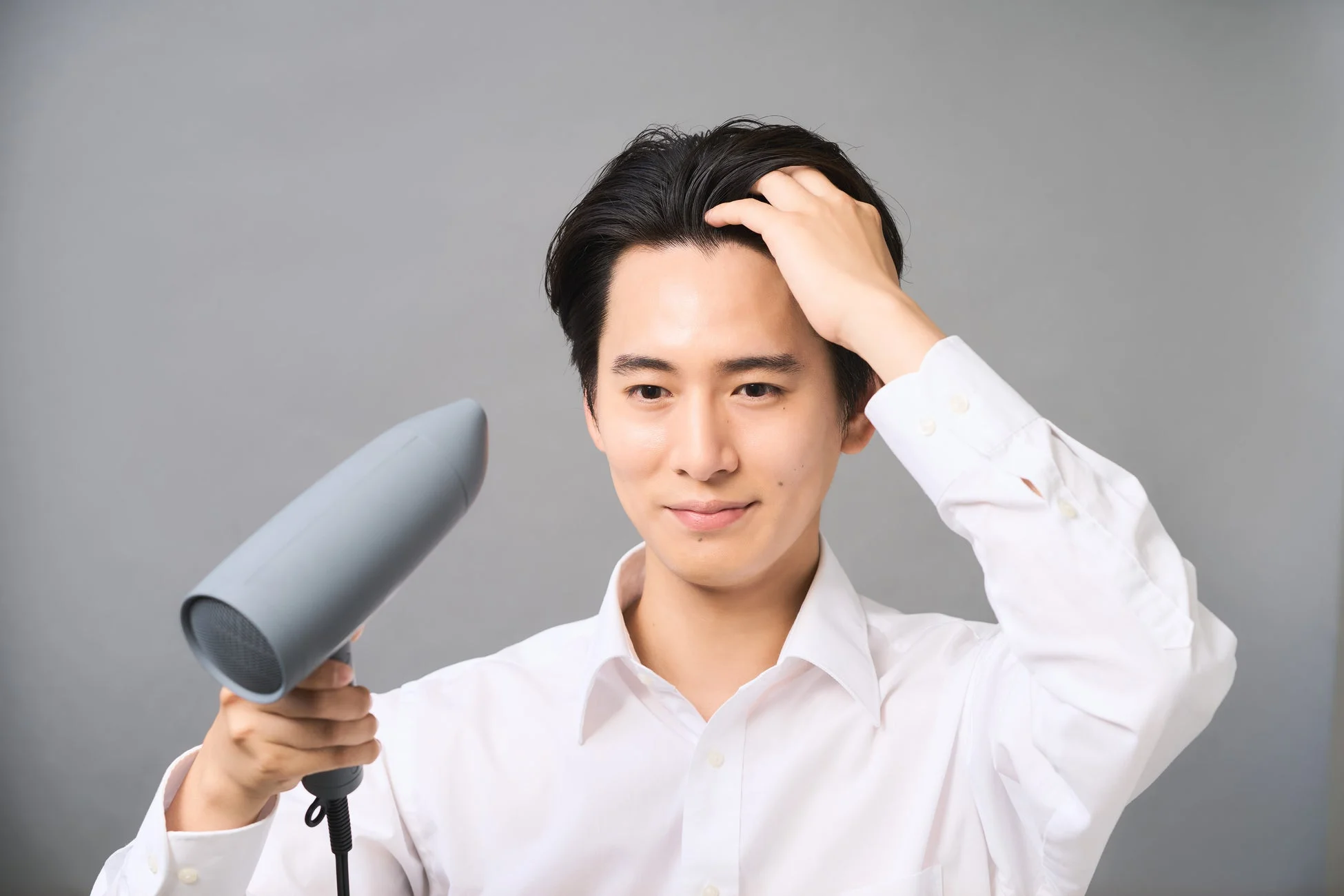 ドライヤーで髪を乾かす男性