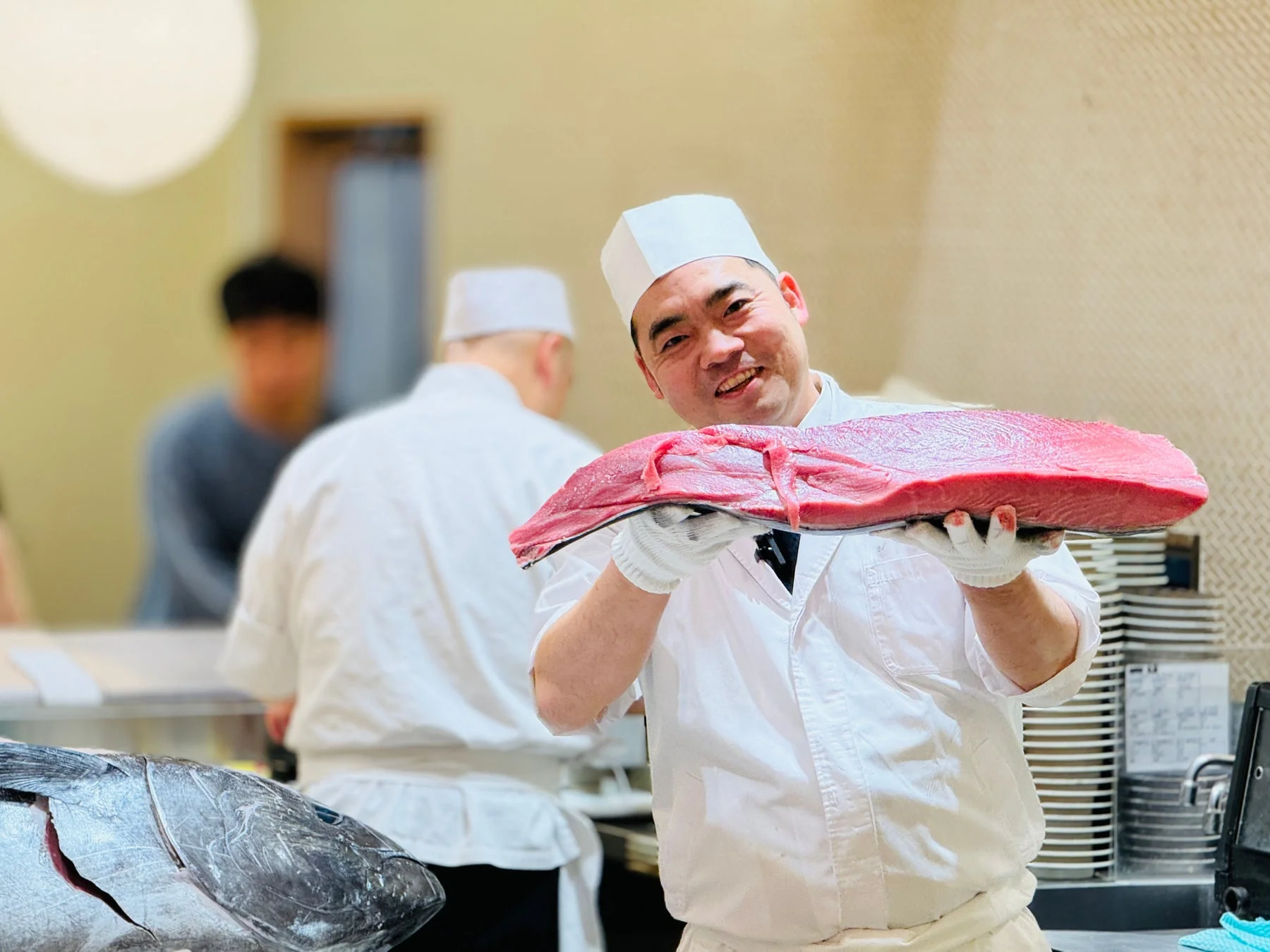 笑顔でマグロを掲げる寿司職人