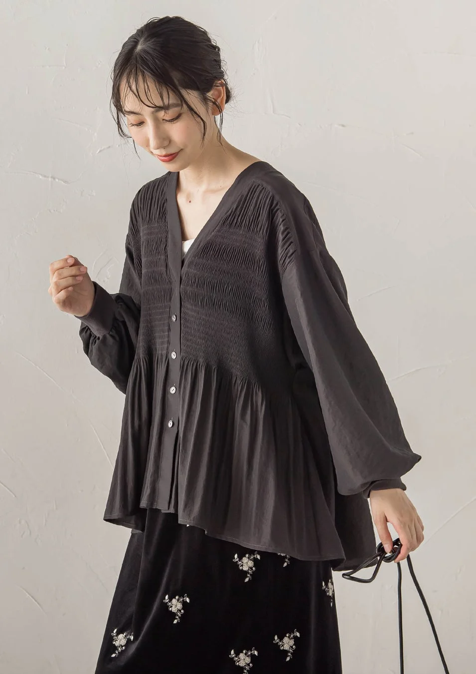 黒いシャーリングブラウスと花柄刺繍の黒いスカートを着用した若い女性