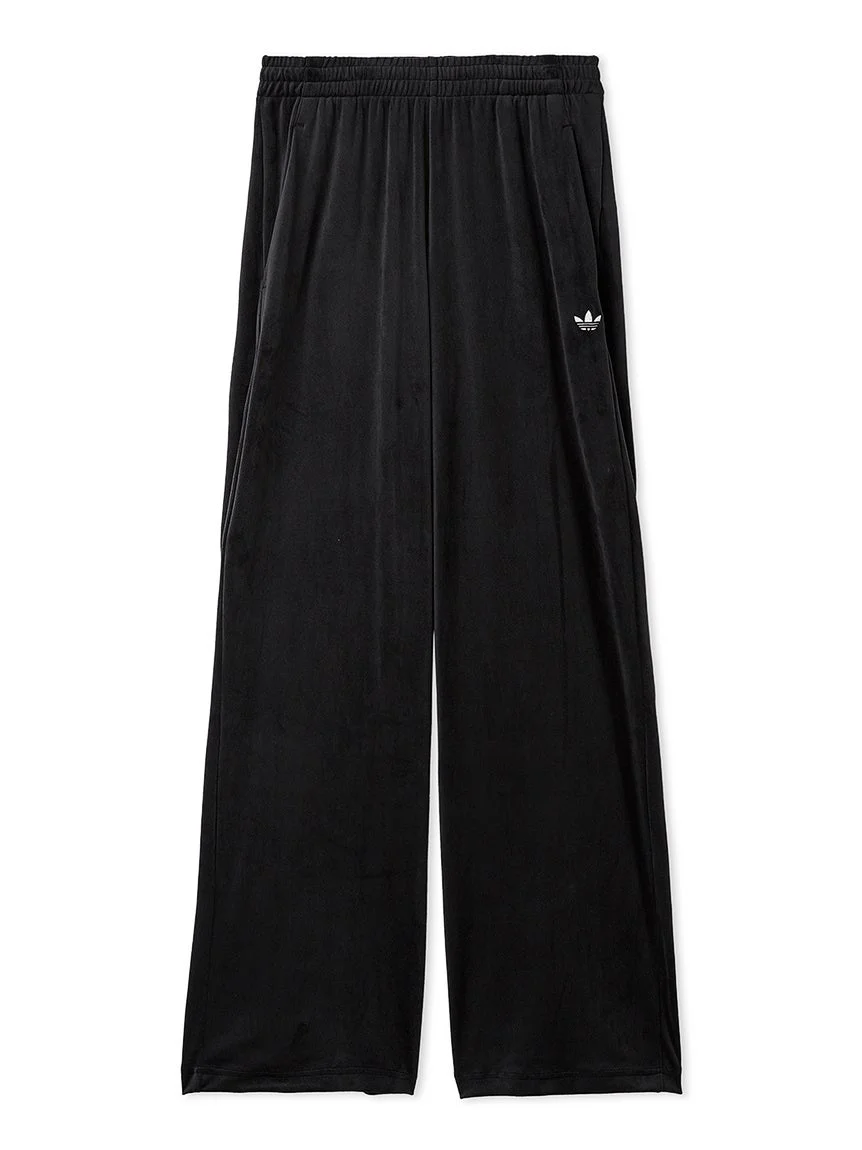 黒いワイドシルエットのアディダス製パンツ