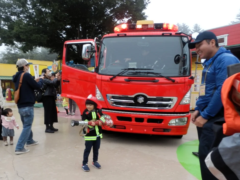 子供が消防士の制服を着て消防車の前でポーズ