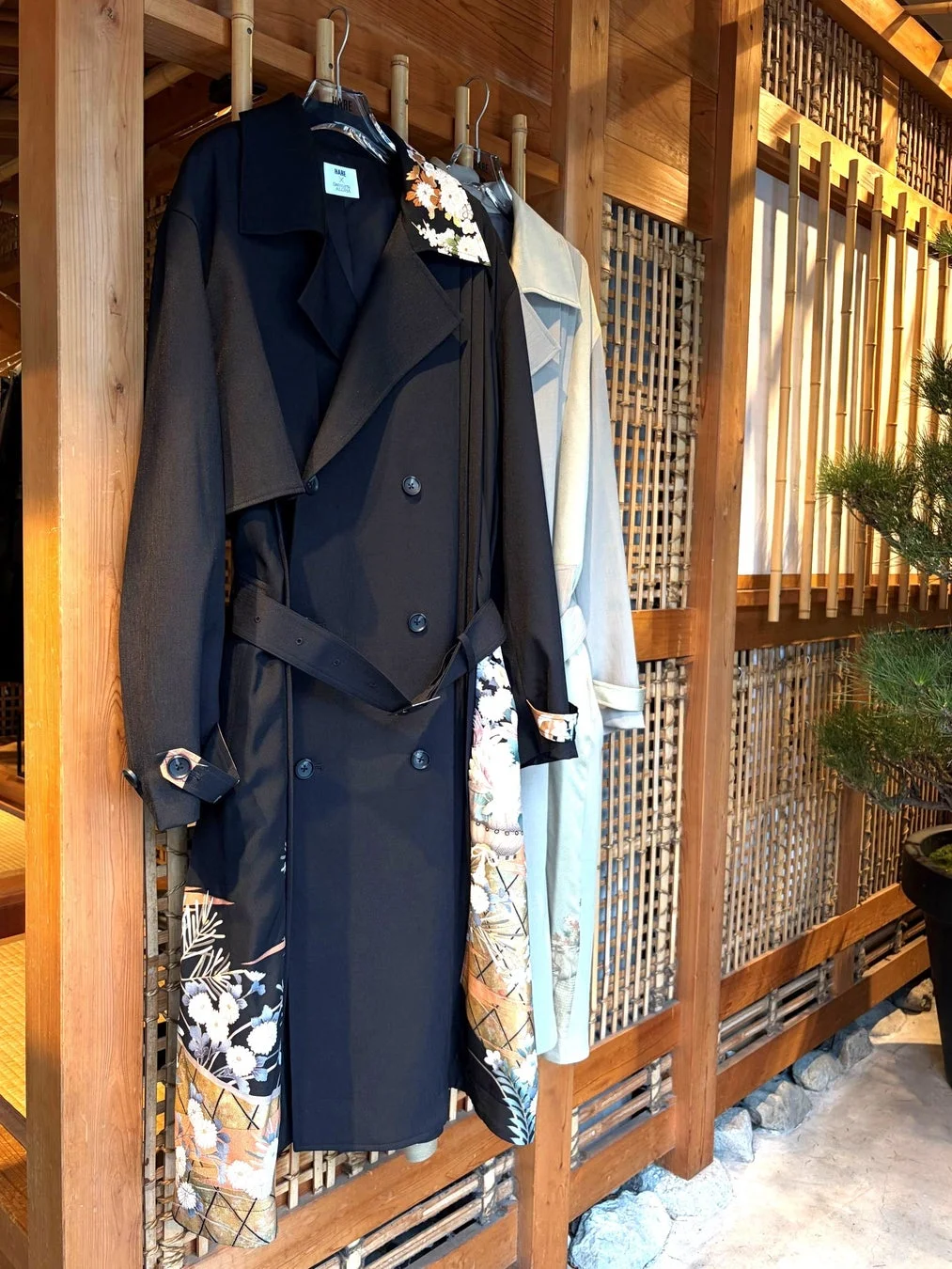 和柄があしらわれた黒いトレンチコート