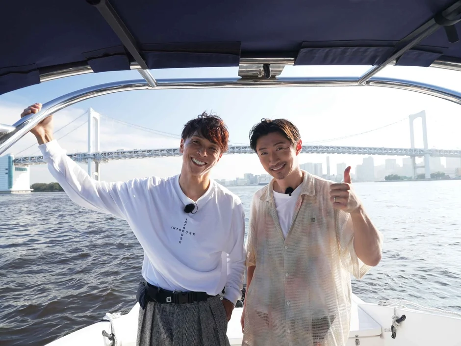 ボートに乗った男性2人とレインボーブリッジ
