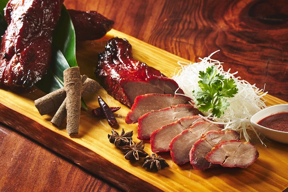 艶やかな赤色の焼き豚が木製ボードに美しく盛り付けられています