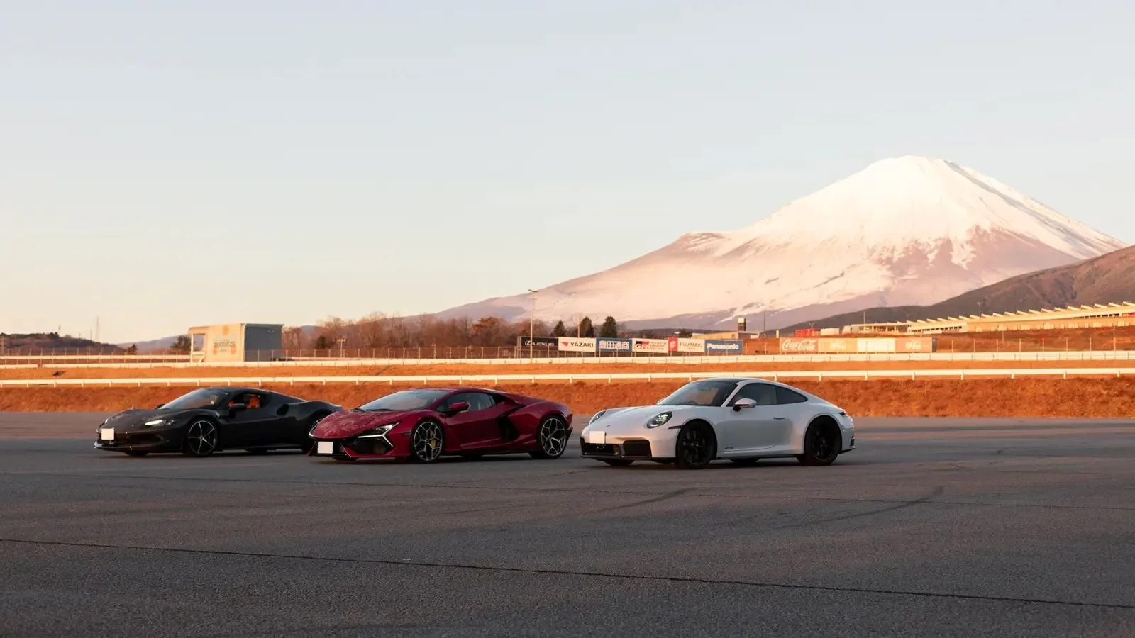 雪化粧した富士山を背景にサーキットに並ぶ高級スポーツカー