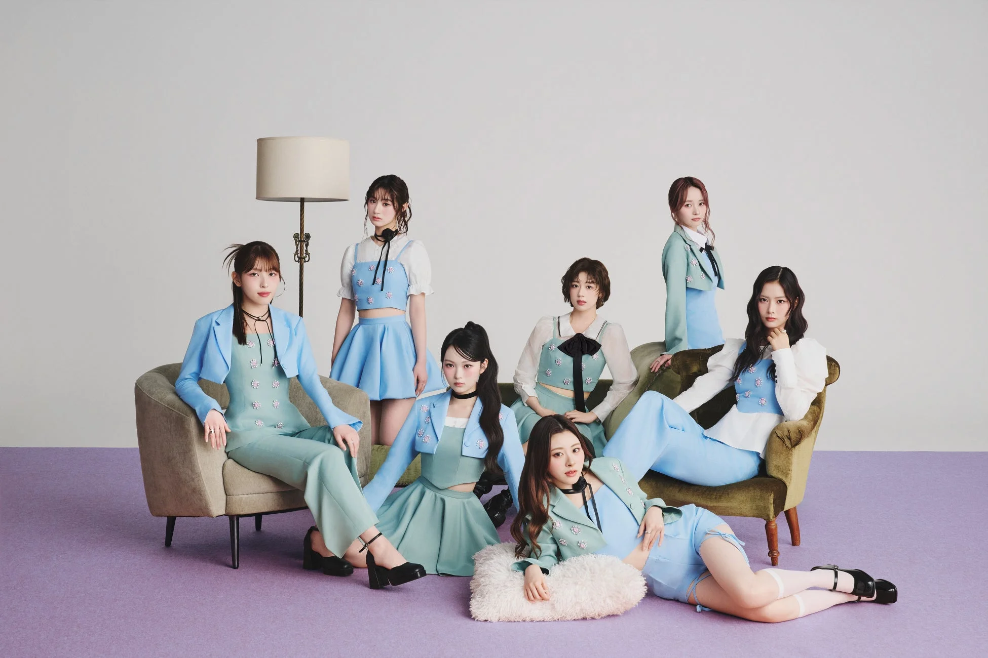 パステルカラーの衣装を着た7人の女性グループが、白い背景のスタジオで撮影された集合写真。