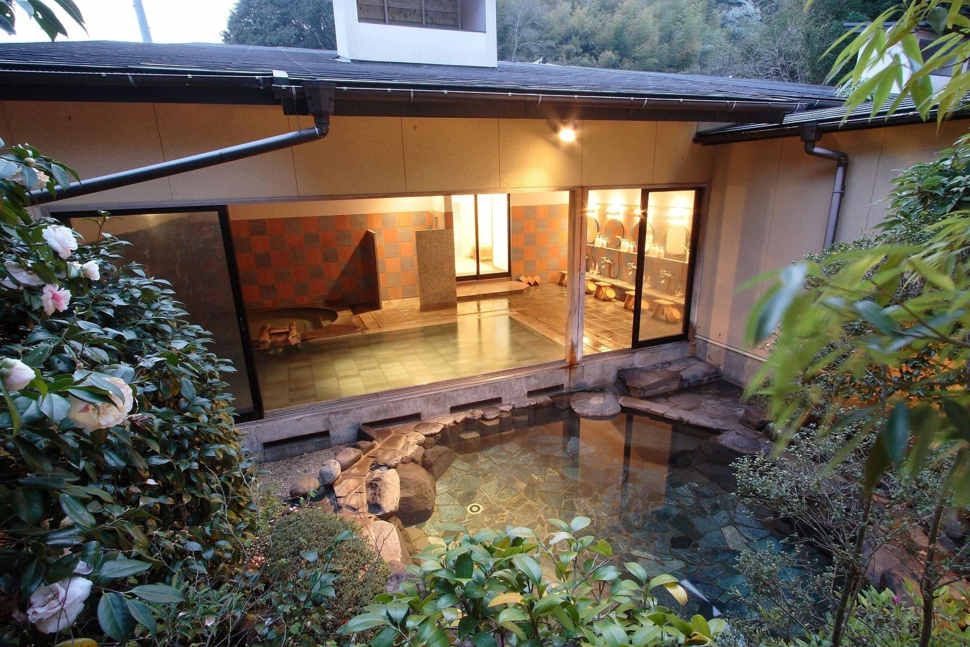 豊かな緑に囲まれた和風の建物に、美しい露天風呂と屋内の浴場