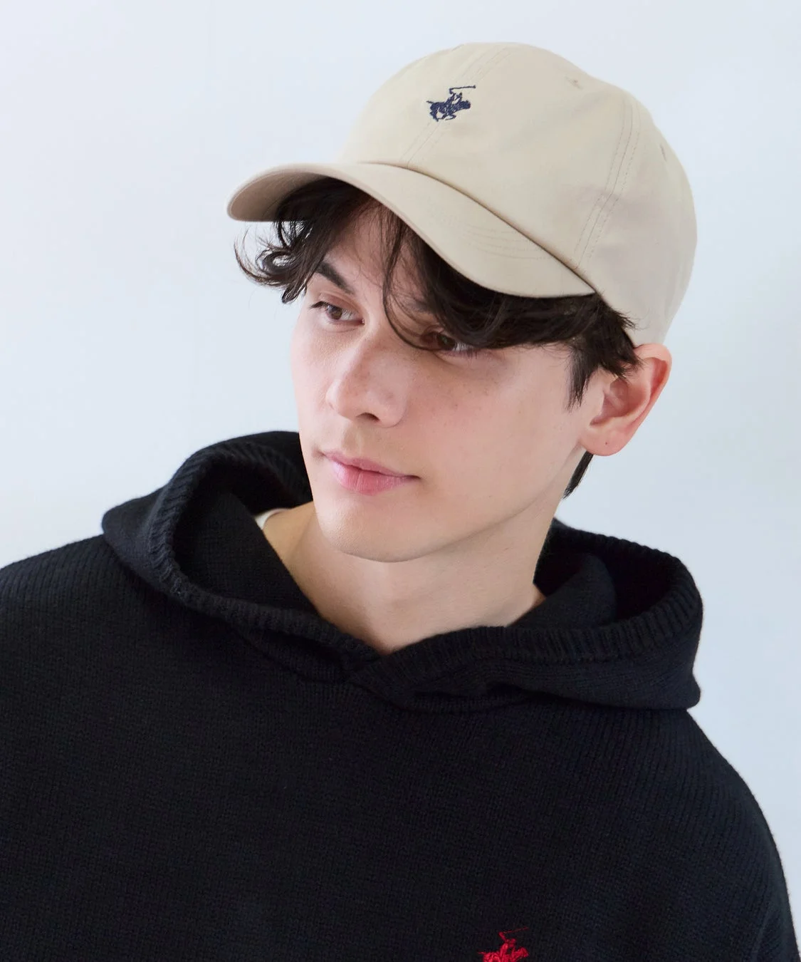 ベージュのキャップと黒いフーディーを着用した男性のポートレート