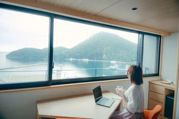 窓辺でノートPCを使う女性