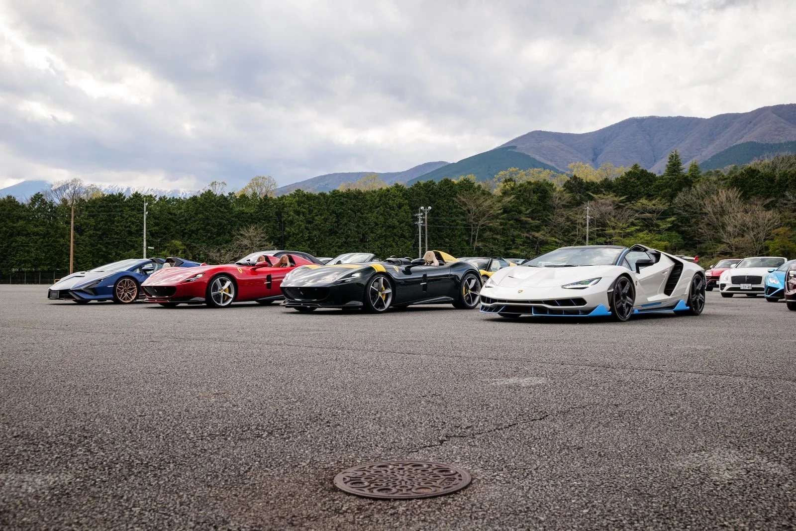 屋外の駐車場に並べられた複数の高級スーパーカー