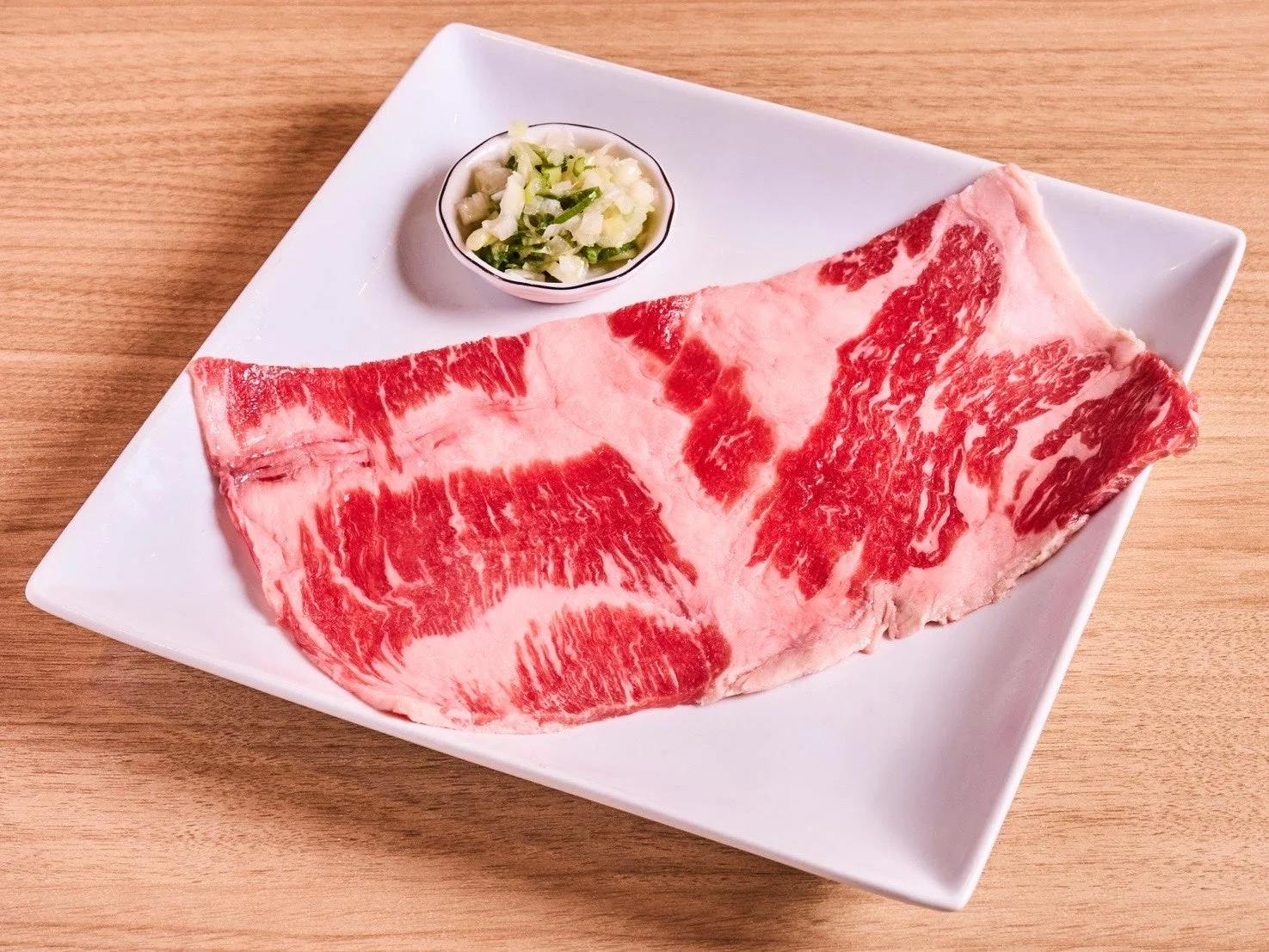 白い皿に盛られた霜降りの生肉