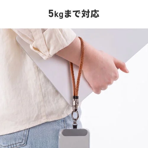編み込みの茶色いリストストラップを腕に通し、スマートフォンを吊り下げている様子を写しています。ストラップは5kgまでの重さに対応していることが示されています。