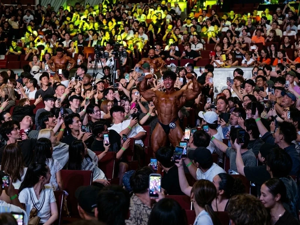 ボディビル大会でステージ上の選手を撮影する観客たち
