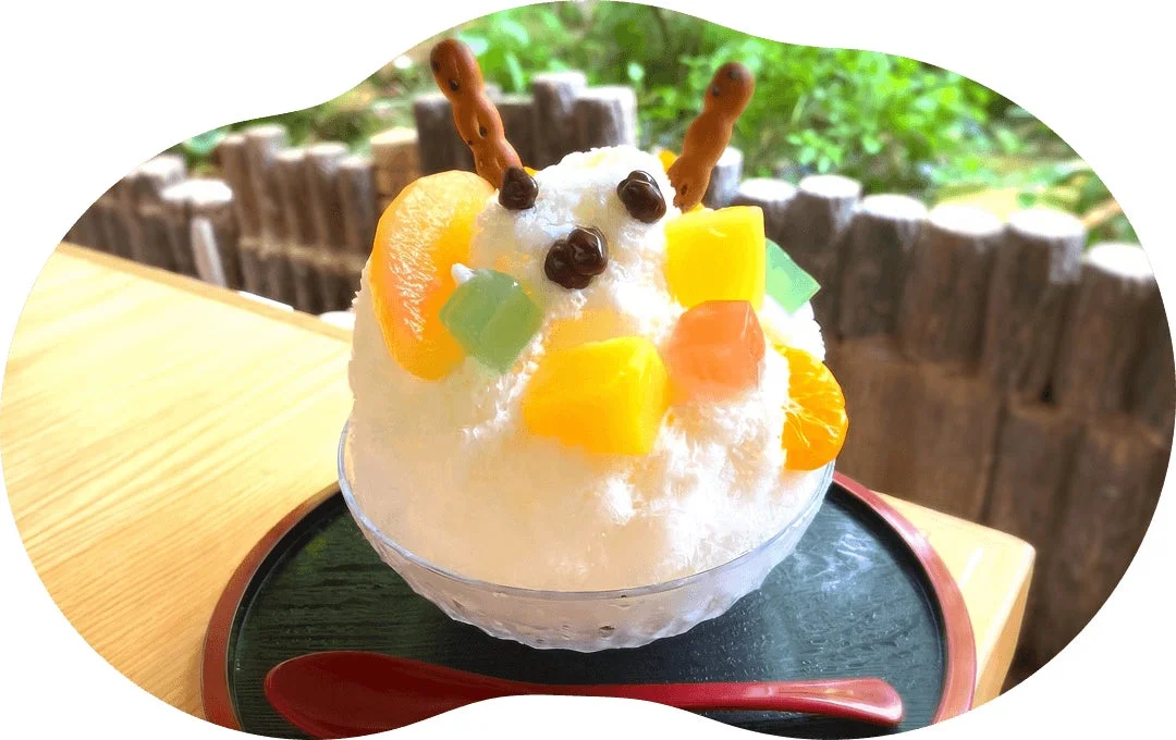フルーツやゼリー、チョコレートなどでカラフルに飾り付けられた、かわいらしい顔のようなかき氷です。