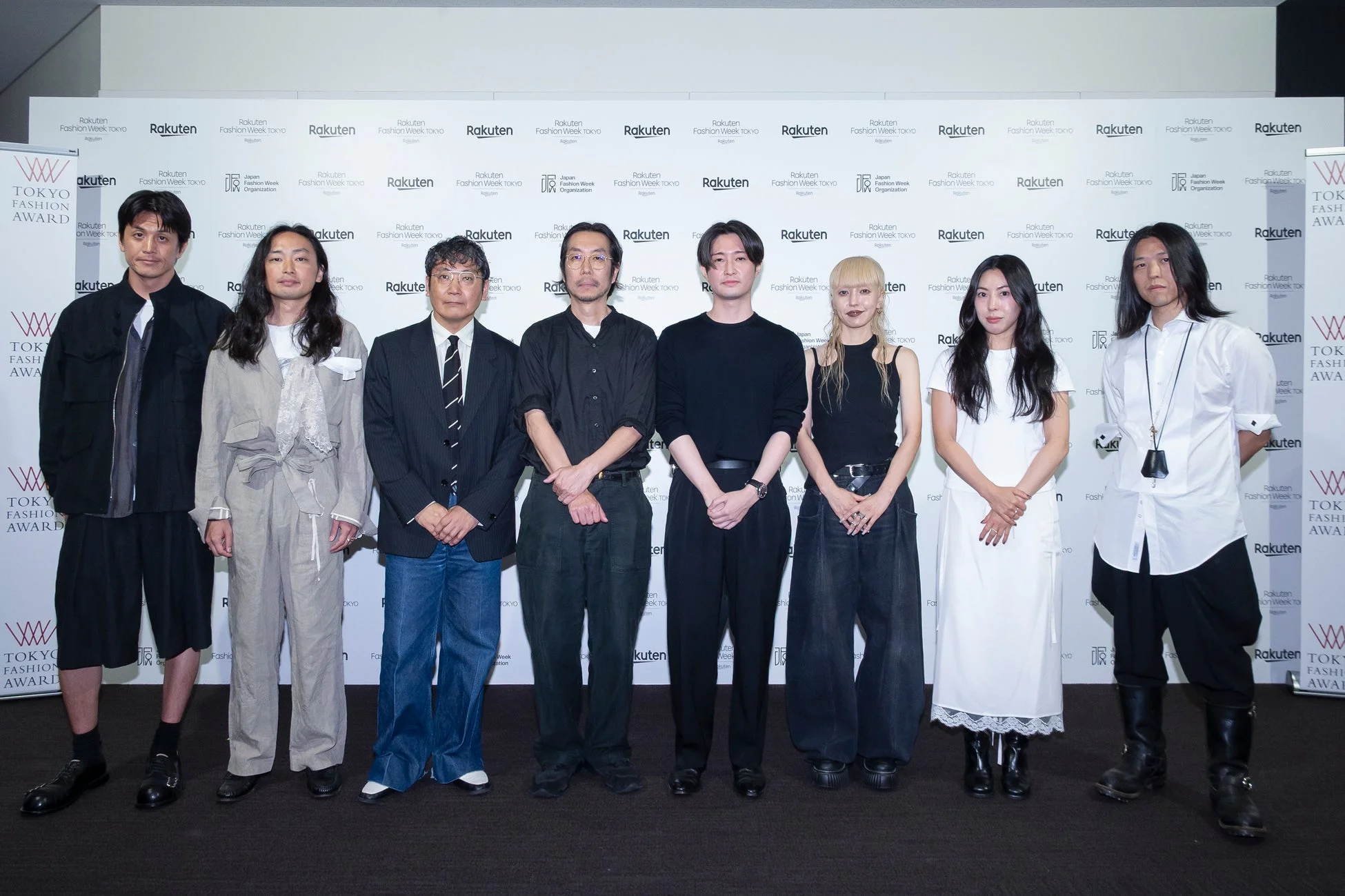 楽天ファッションウィーク東京のイベントで、8人の男女がカメラに向かって立っている