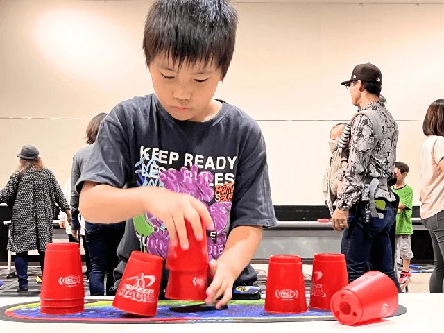 少年が赤いカップを素早く積み重ねるスポーツスタッキングに集中している様子