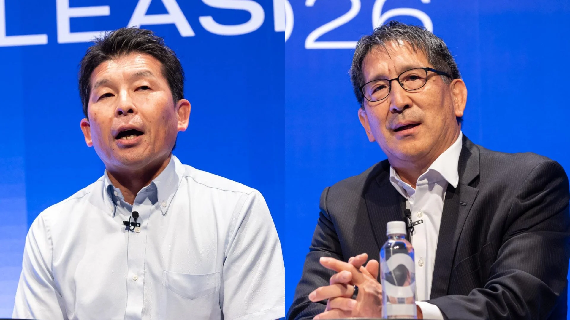 青い背景の前で2人の日本人男性が会議やプレゼンテーションに参加している様子。一人は発言中で、もう一人はスーツ姿で水筒を前にしている。