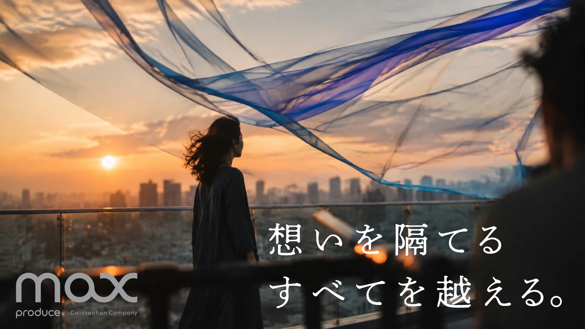 夕焼けに染まる街並みを屋上から眺める女性