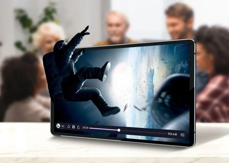 宇宙飛行士がタブレット画面から飛び出すような3D映像を映し出しており、その没入感あふれる視聴体験を複数の人々が楽しんでいる様子です。未来的なエンターテイメント技術を象徴しています。